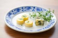 cultured butter pats with fresh herbs on porcelain plate