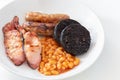 Cumberland sausages, bacon, baked beans and black pudding in a white bowl Royalty Free Stock Photo