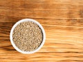 Cumin jeera seeds in white bowl on brown wood background with copy space