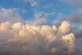 Cumulonimbus clouds against the blue sky. Picturesque cumulus clouds in the yellow light of the setting sun. Dramatic