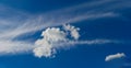 Cumulus clouds against the background of stripes of stratus clouds on a blue sky Royalty Free Stock Photo