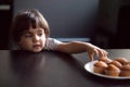 Cunning cute little girl stealing delicious muffin on table