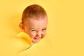 The cunning face of a child looks out of a hole in the studio yellow bac