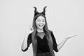 cunning little demon presenting product. halloween devil girl. happy childhood. funny teen child in imp horns. cheerful