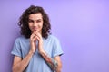 Cunning sly scheming male with curly hair wearing t-shirt keeping hands together as having cunning evil idea