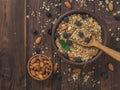 A Cup of almonds and a clay bowl of granola on a wooden table.