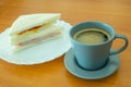 A Cup of Americano Black Coffee and Ham With Egg Sandwich on The Wooden Table