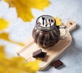 Cup of aroma hot chocolate with marshmallows on a light blue background with autumn maple leaves. Concept cozy drink. Front view