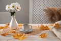 Cup of aromatic coffee, beautiful flowers and autumn leaves on white wooden table indoors, space for text Royalty Free Stock Photo