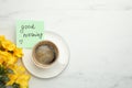 Cup of aromatic coffee, beautiful yellow freesias and Good Morning note on white marble table, flat lay. Space for text Royalty Free Stock Photo