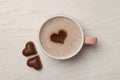 Cup of aromatic coffee with heart shaped decoration and chocolate candies on white wooden table, flat lay Royalty Free Stock Photo