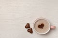 Cup of aromatic coffee with heart shaped decoration and chocolate candies on white wooden table, top view. Space for text Royalty Free Stock Photo