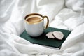 Cup of coffee, notebook and cookies on white bed linen. Cozy morning Royalty Free Stock Photo