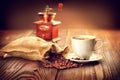 Cup of aromatic coffee on saucer with sack full of roasted coffe Royalty Free Stock Photo