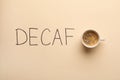 Cup of aromatic coffee and word Decaf on beige background, top view