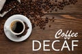 Cup of aromatic decaf coffee and beans on wooden table, flat lay