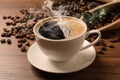 Cup of aromatic hot coffee and beans on wooden table, closeup Royalty Free Stock Photo