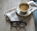 A cup of aromatic strong coffee on an saucer with a vintage spoon. Newspaper and glasses on the table Royalty Free Stock Photo