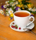 cup of aromatic tea, wild strawberry, bouquet of wild flowers on a wooden background Royalty Free Stock Photo