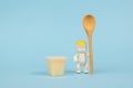 A cup of banana dessert and a baby figurine with a spoon. The concept of healthy baby food