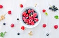 Cup with berries and a row of currant and raspberry berries and leaves on white wooden background, pattern background Royalty Free Stock Photo