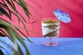 Cup of biscuit sand with coffee mouse, decorated with a blue umbrella on a flat red and blue background