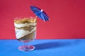 Cup of biscuit sand with coffee mouse, decorated with a blue umbrella on a flat red and blue background. Copy space