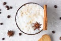 Cup of black coffee or cappuccino with milk foam decorated with anise star and cinnamon stick on light grey table with gingerbread