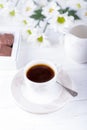 Porcelain cup of black coffee, chocolate candies and chrysanthemums flowers on a white background Royalty Free Stock Photo