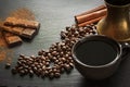 Cup of black coffee, coffee beans, chocolate bar, cinnamon and old copper cezve on black slate as background with copy space. Royalty Free Stock Photo
