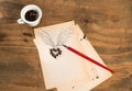 Cup of black coffee with coffee beans heart with wings drawn in pencil and red pen on a blank sheet