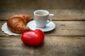 Cup of black coffee with croissant and red heart candle