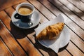 Cup of black coffee and a croissant on a table in a street cafe. Selective focus Royalty Free Stock Photo