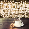 Cup of black coffee on wooden table in cafe. Christmas lights and gold garland on background Royalty Free Stock Photo