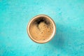 A cup of black coffee with froth, overhead flat lay shot on blue Royalty Free Stock Photo