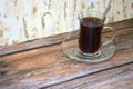 A cup of black coffee on a glass saucer with a spoon on a wooden table. Close-up Royalty Free Stock Photo