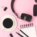 Cup of black coffee, headphones, notepad and stationery.