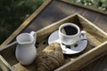 A cup of black coffee, milk and a croissant on a wooden table against the background of nature Royalty Free Stock Photo