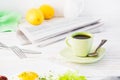 A cup of black coffee, a newspaper and cutlery on a white table