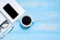 Cup of black coffee and smart phone with office supplies; pen, notebook and eyes glasses on wooden table background Royalty Free Stock Photo