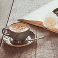 Cup of black coffee and open book with white rose on wooden board. Vintage toned. Close up. Royalty Free Stock Photo