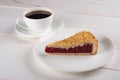 A cup of black coffee and a piece of berry pie on a plate stand on a white wooden table Royalty Free Stock Photo