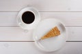 A cup of black coffee and a piece of berry pie on a plate stand on a white wooden table. Top view Royalty Free Stock Photo