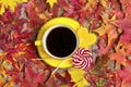 Cup with black coffee, red, yellow lollipops on wooden table with autumn fallen yellow, orange and red leaves Royalty Free Stock Photo