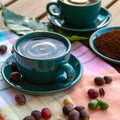Cup with black coffee served outside with raw green, mature red and roasted coffee beans, decorated with green leaves from coffee
