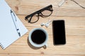 Cup of black coffee and smart phone with office supplies; pen, notebook and eyes glasses on blue wooden table background Royalty Free Stock Photo