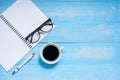 Cup of black coffee and smart phone with office supplies; pen, notebook and eyes glasses on wooden table background Royalty Free Stock Photo