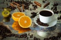 A cup of black coffee with spilled coffee beans, pieces of orange, sticks of cinnamon and kiwi. Photo in vintage style