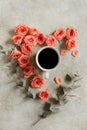 Cup of black coffee surrounded with fresh coral roses