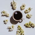 A cup of black coffee on the table with a branch of lilac, top view. Coffee and different lilac flowers. Royalty Free Stock Photo